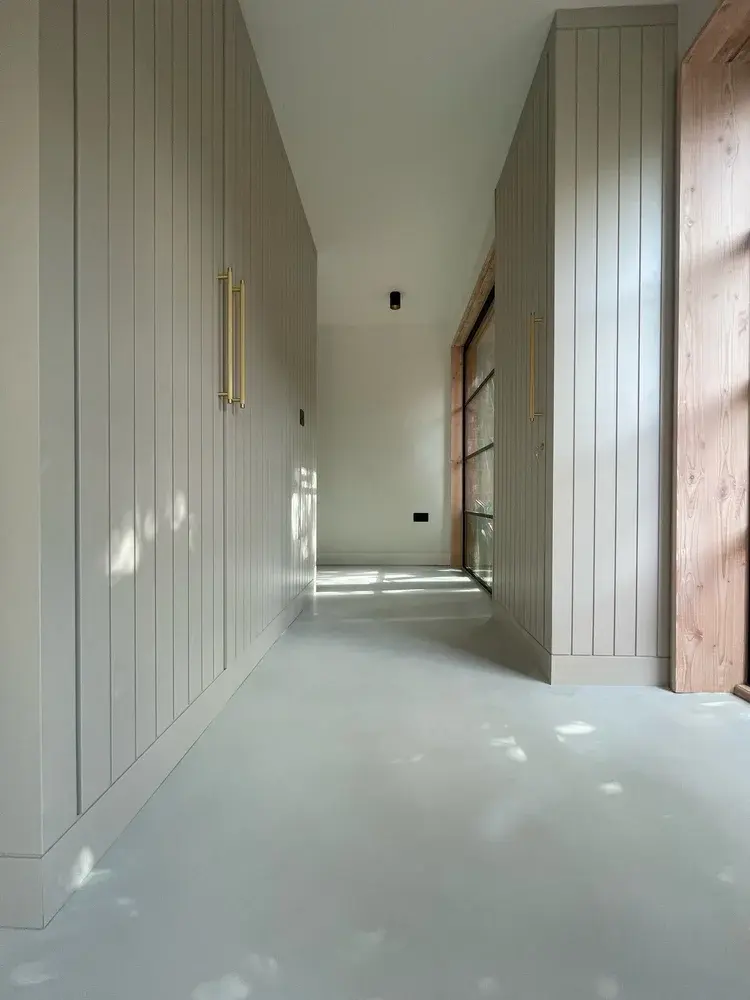 Microcement floor meeting kitchen cabinetry with continuous seamless finish — Beaumaris