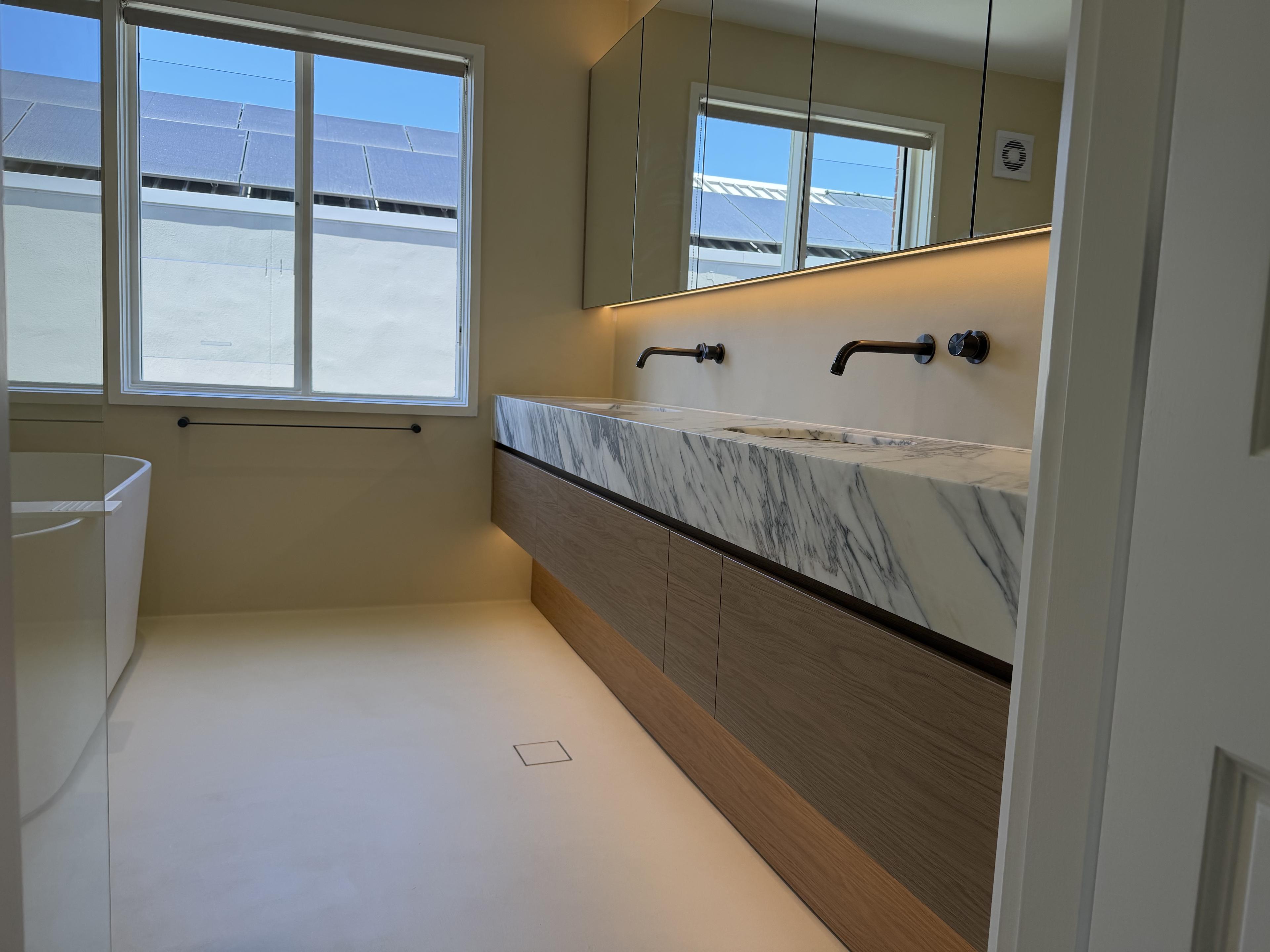 Wide context shot showing the full microcement bathroom — Malvern